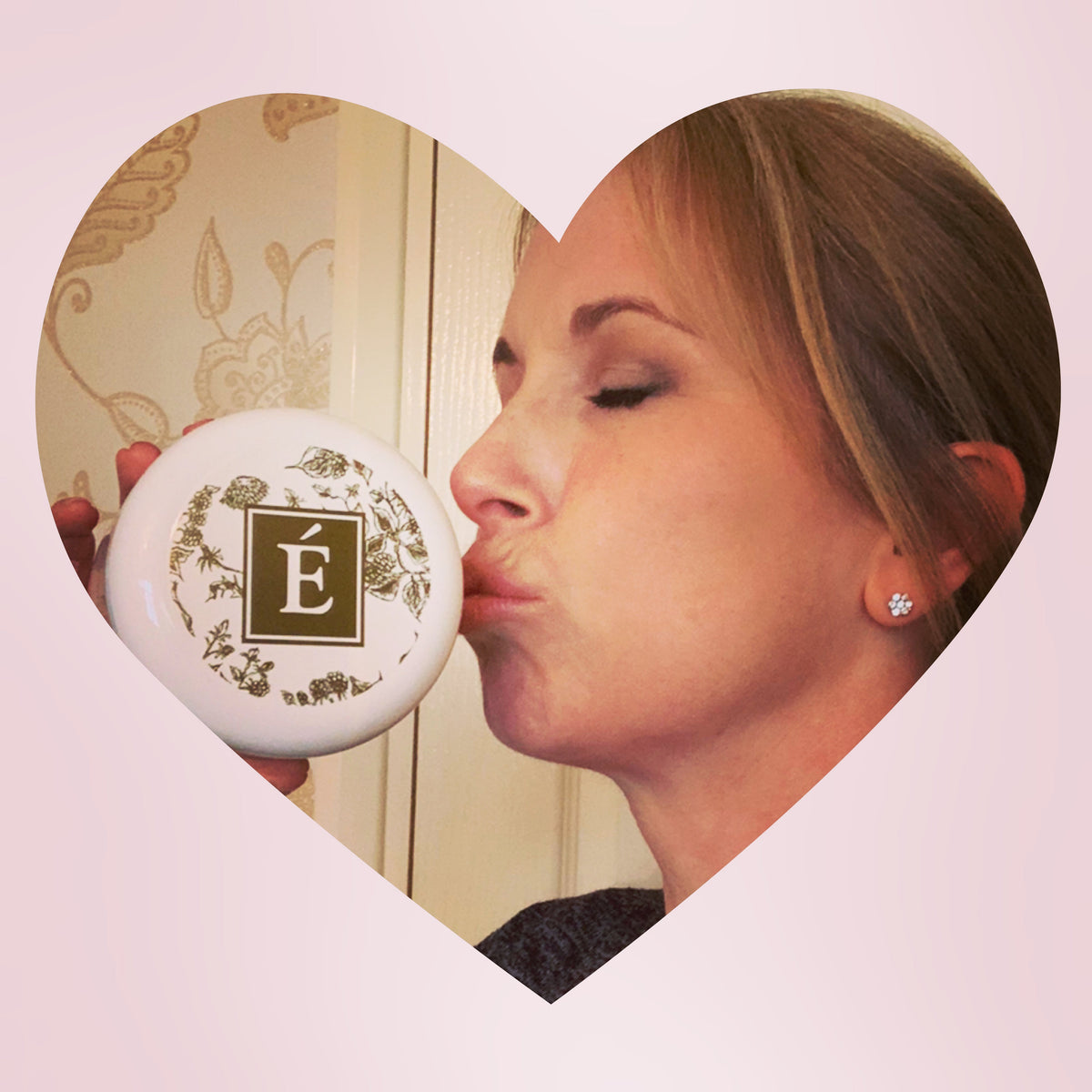 Karen kissing an Éminence-branded round mirror in a heart-shaped photo.