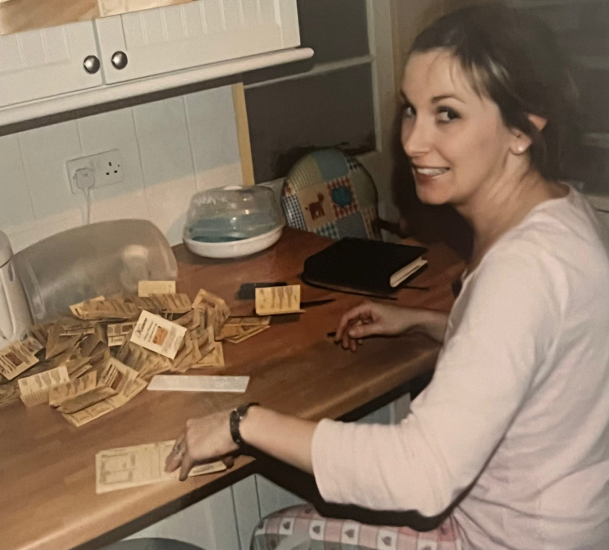 Karen preparing handmade beauty treatment price lists at her kitchen counter.