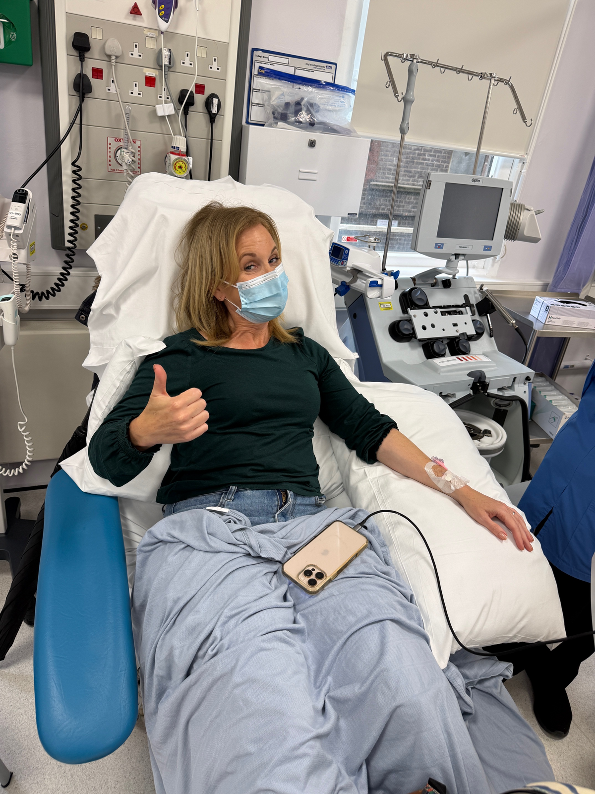 Karen giving a thumbs-up from a hospital chair during her stem cell donation at King’s College Hospital.
