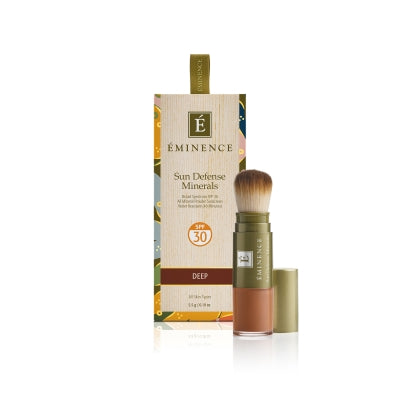 A box of Éminence Organic Sun Defense Minerals with SPF 30, showing the product name and the shade 'deep'. The product comes with a flow-through brush for application.