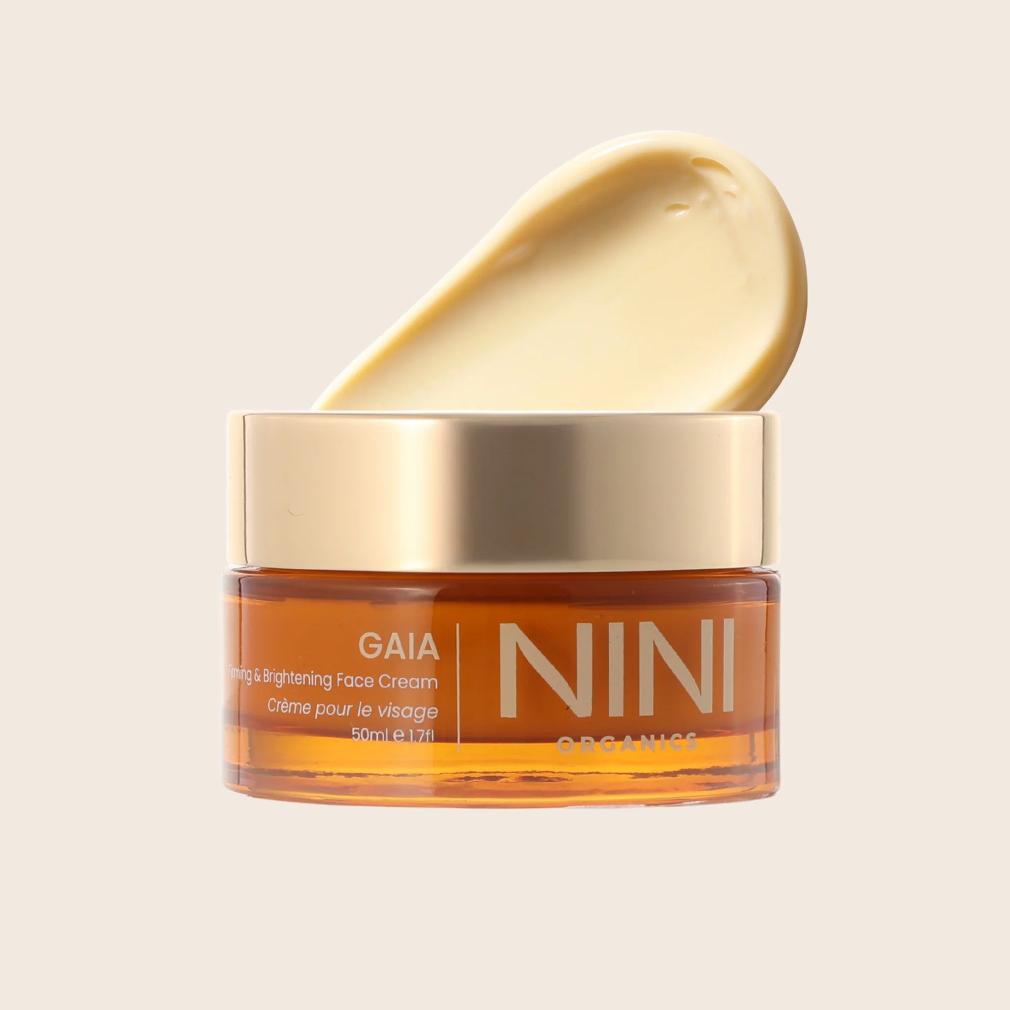 NINI GAIA face cream jar with a gold lid on a beige background and swatch