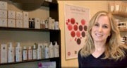 Female therapist in treatment room head shot with Éminence skincare products on shelf
