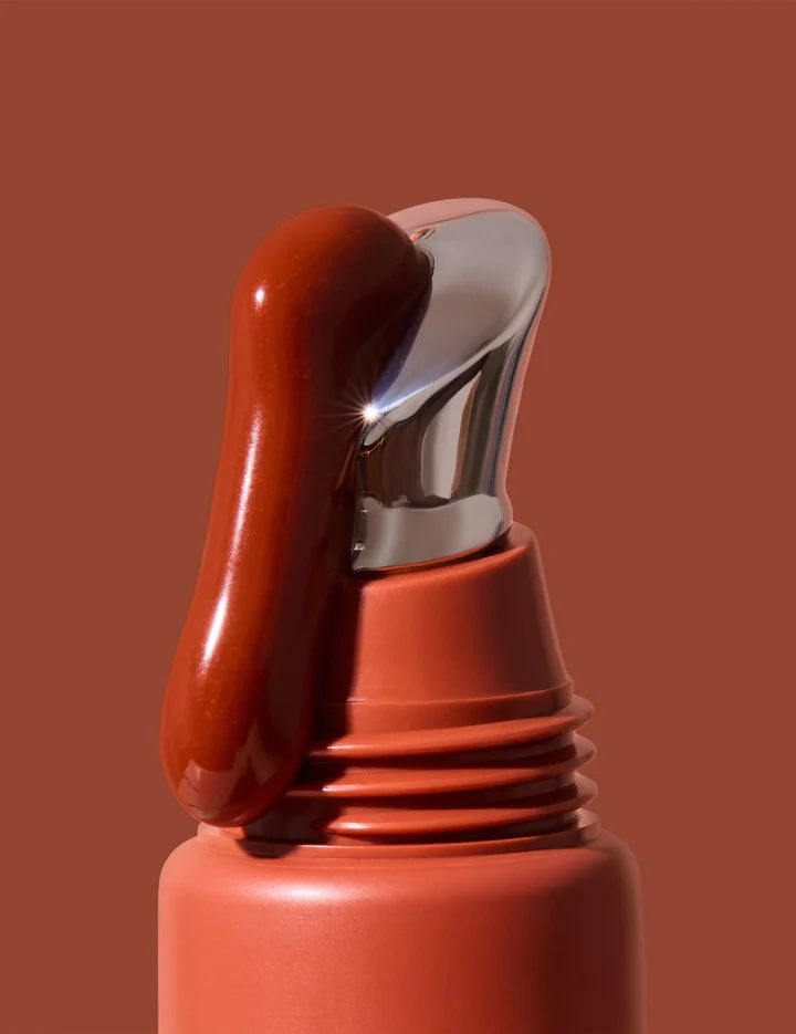 Close-up of a red spray bottle with a silver nozzle on a brown background