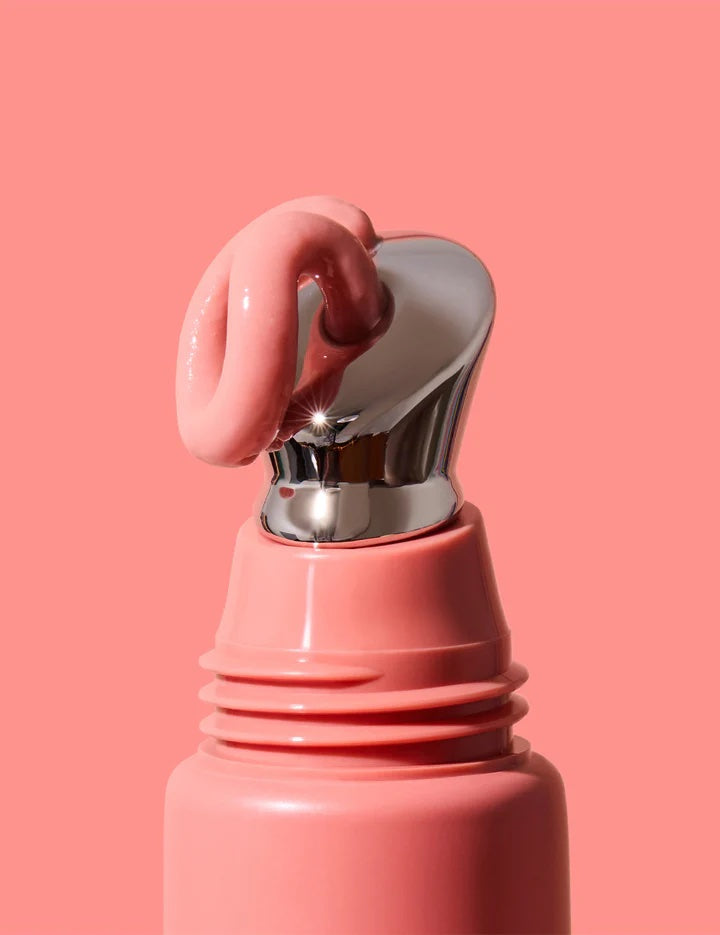 Close-up of a pink bottle with a silver cap on a pink background
