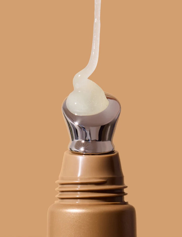 Close-up of a cosmetic bottle with a droplet of cream on a beige background
