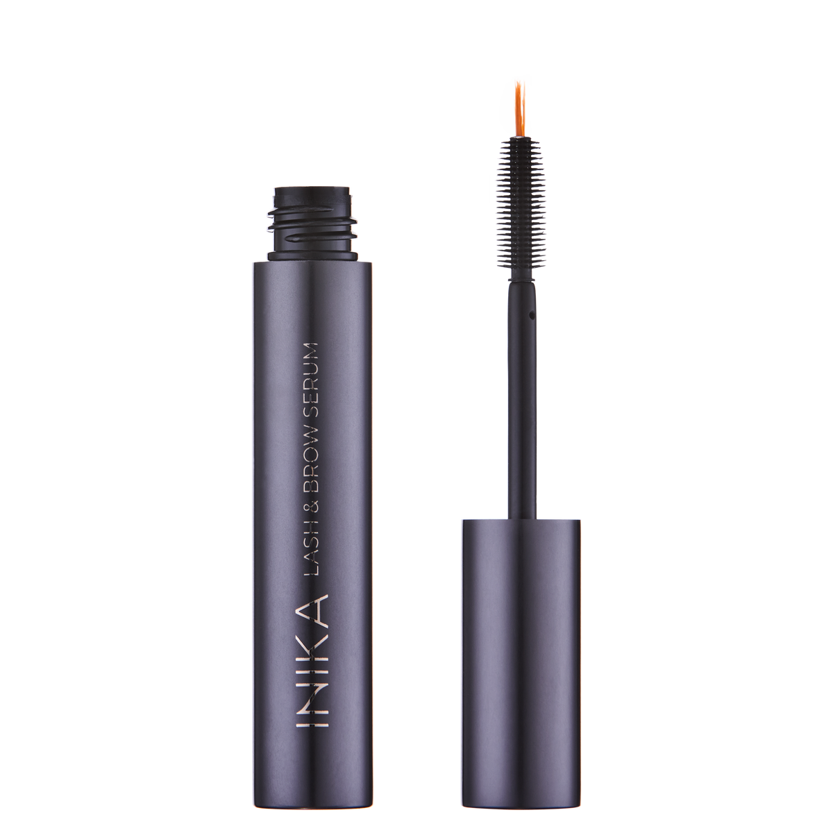 A bottle of INIKA Organic Lash and Brow Serum with the cap removed, showing the applicator brush with bristles coated in serum.