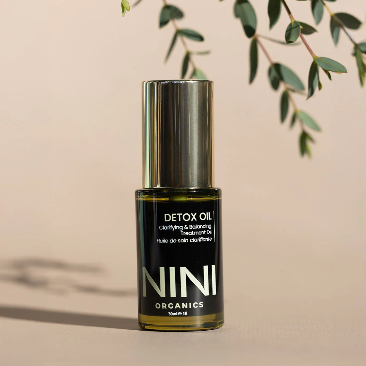 NINI Organics detox oil bottle with a plant in the background