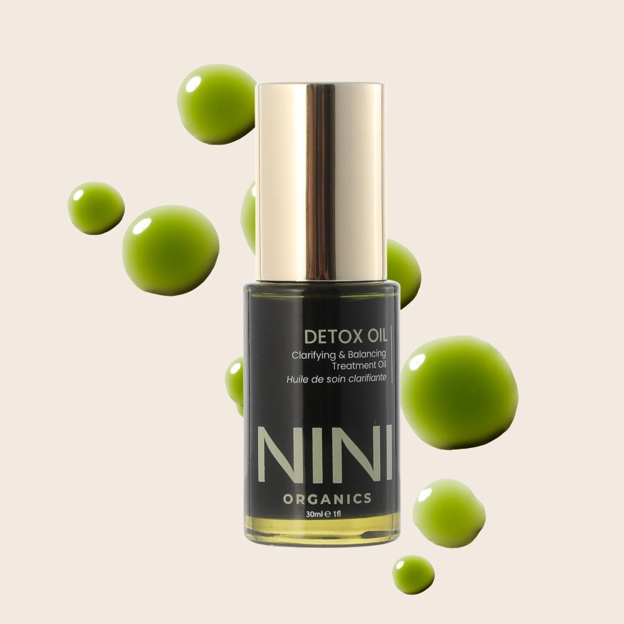 NINI Organics detox oil bottle with green droplets on a beige background