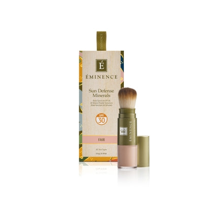 A box of Éminence Organic Sun Defense Minerals with SPF 30, showing the product name and the shade 'Fair'. The product comes with a flow-through brush for application.