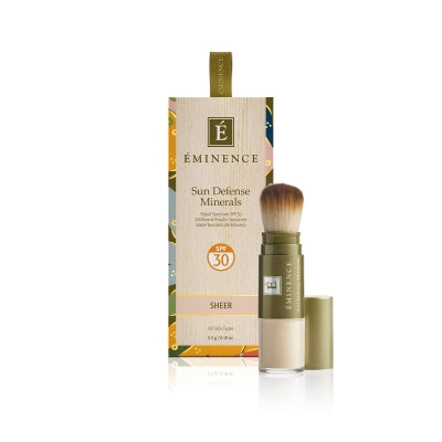 A box of Éminence Organic Sun Defense Minerals with SPF 30, showing the product name and the shade 'Sheer'. The product comes with a flow-through brush for application.