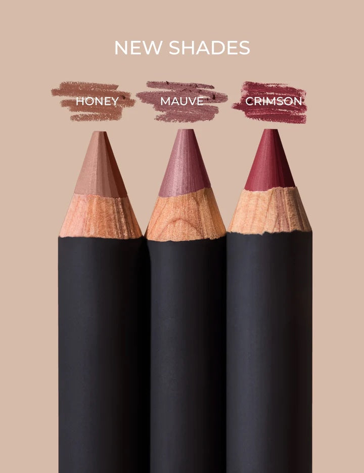 Three black makeup pencils with color swatches labeled 'Honey', 'Mauve', and 'Crimson' on a beige background.