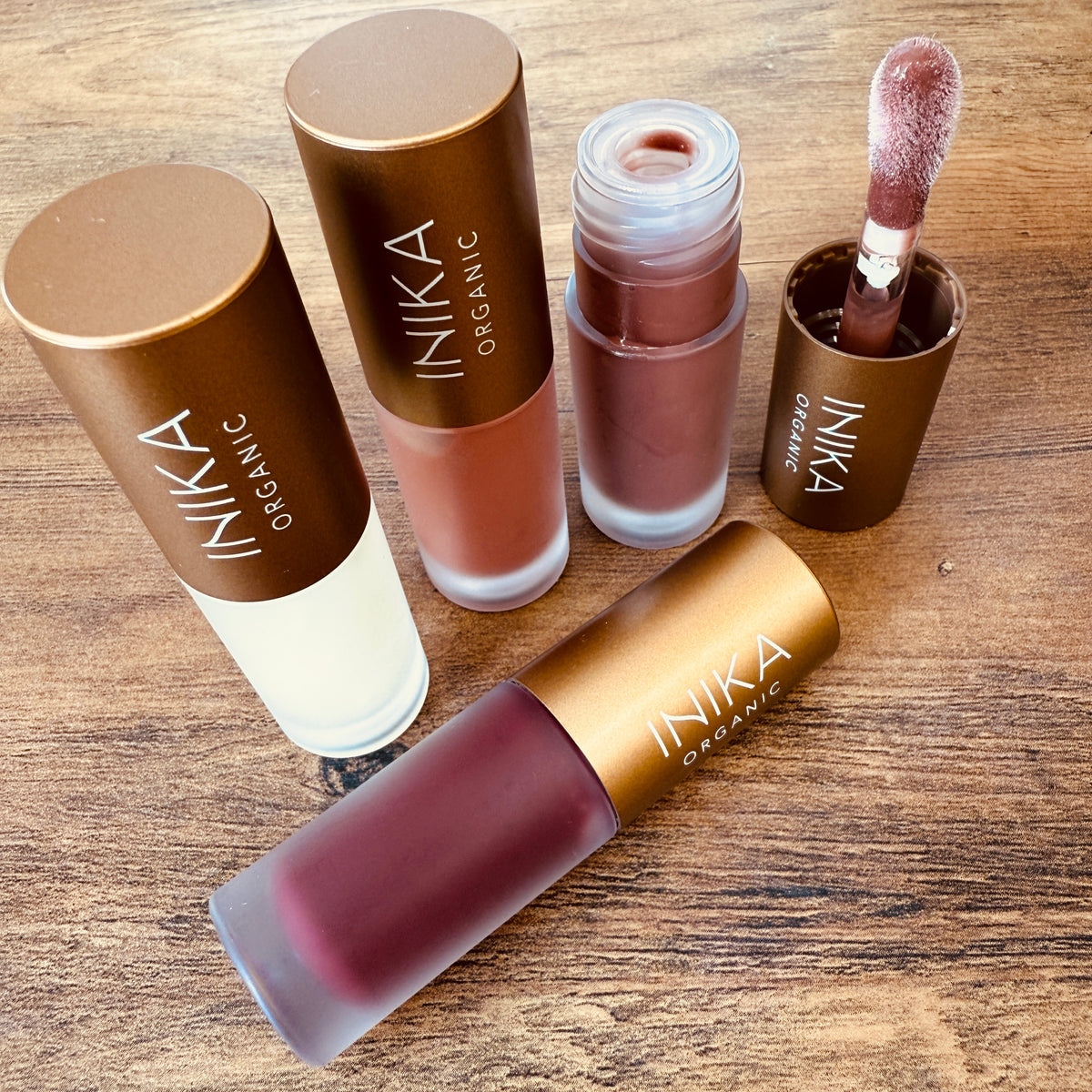 Inika organic lip products on a wooden surface