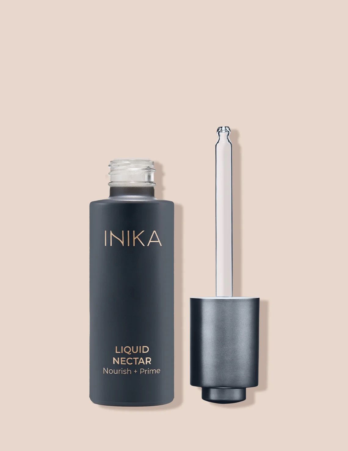 A glass bottle with a dropper applicator labeled INIKA Liquid Nectar Primer, with a cap on the side.