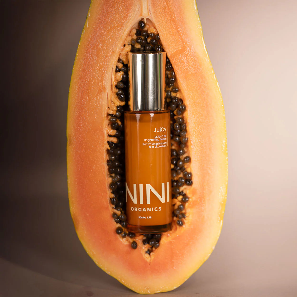 NINI Organics vitamin C serum bottle inside a halved papaya on a gradient background