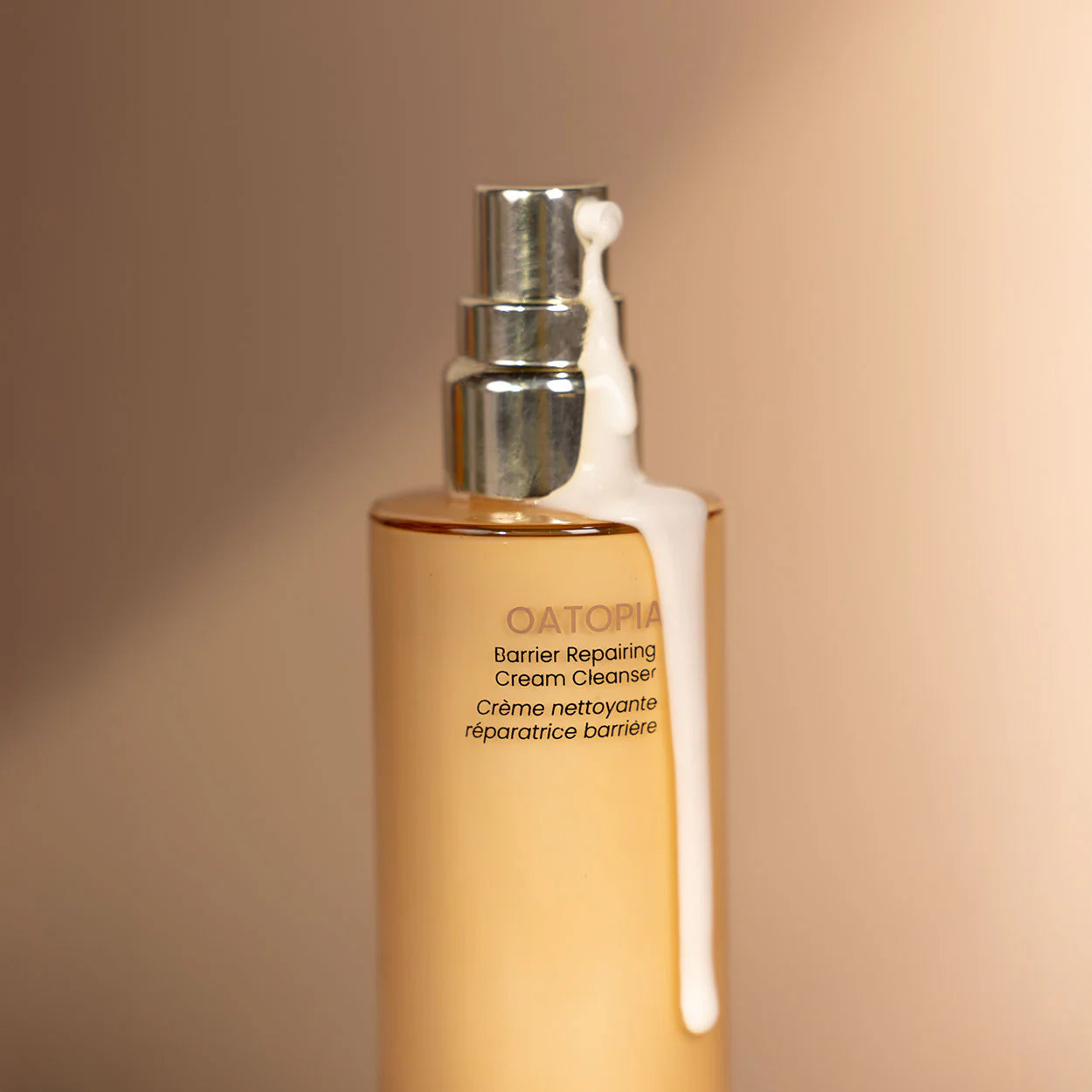 Cream Cleanser bottle with pump on a beige background with product dispensed