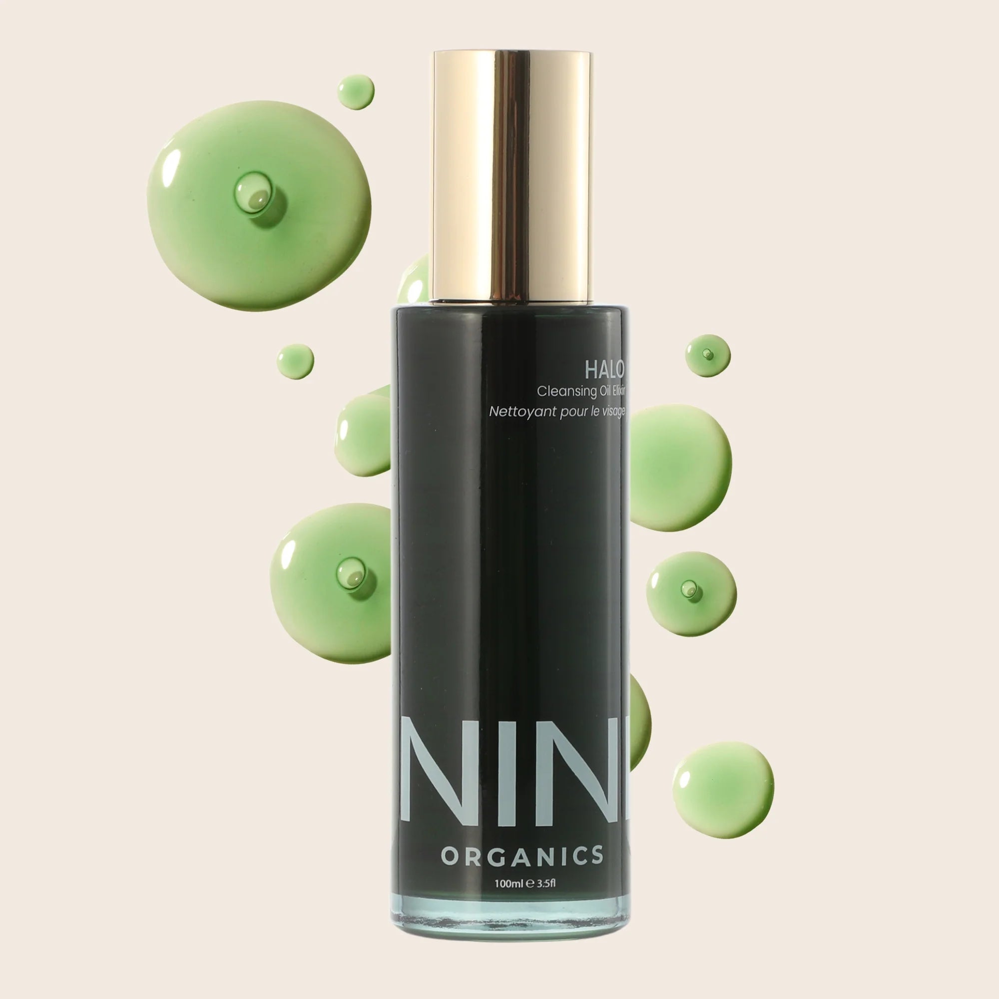 NIN Organics Halo Cleansing oil elixir skincare bottle with green droplets on a beige background
