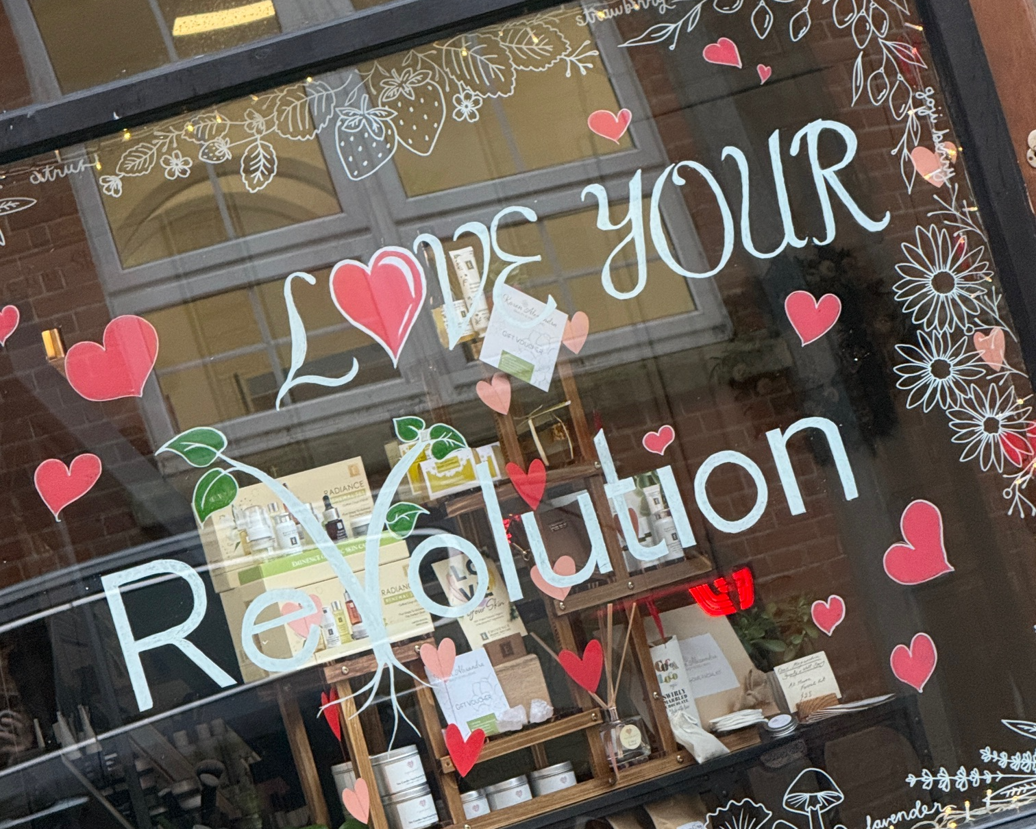 Store window display with decorative text and hearts, featuring a product shelf.
